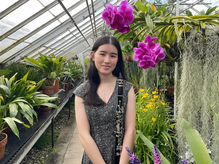 Jessica Klurfeld holding a clarinet in a greenhouse